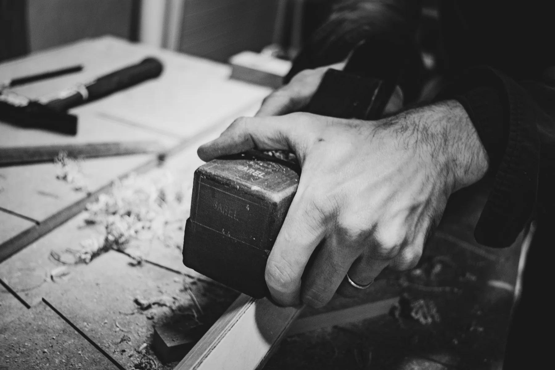 Hände bei der präzisen Bearbeitung eines kleinen Werkstücks aus Holz